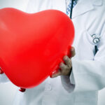 Médecin qui tient dans ses mains un coeur sujet à l'hypertension que les compléments alimentaires dédiés aux troubles Cardiovasculaires permettent de soigner naturellement